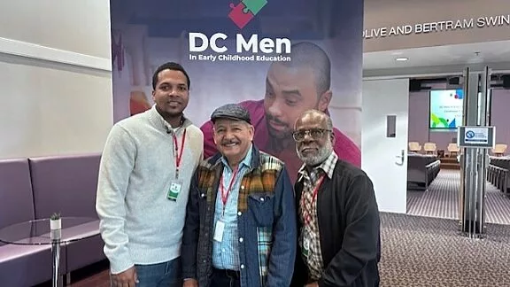 DC Men Conference Photo in Front of Decal