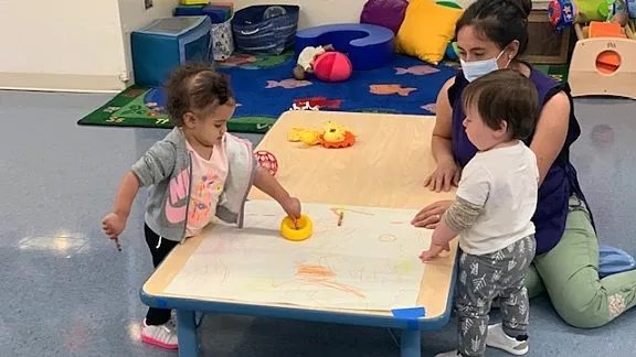 ECE-2.jpg Two Children and a Teacher Playing at a Table